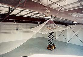 Image of bird netting being installed on the ceiling of a new warehouse.